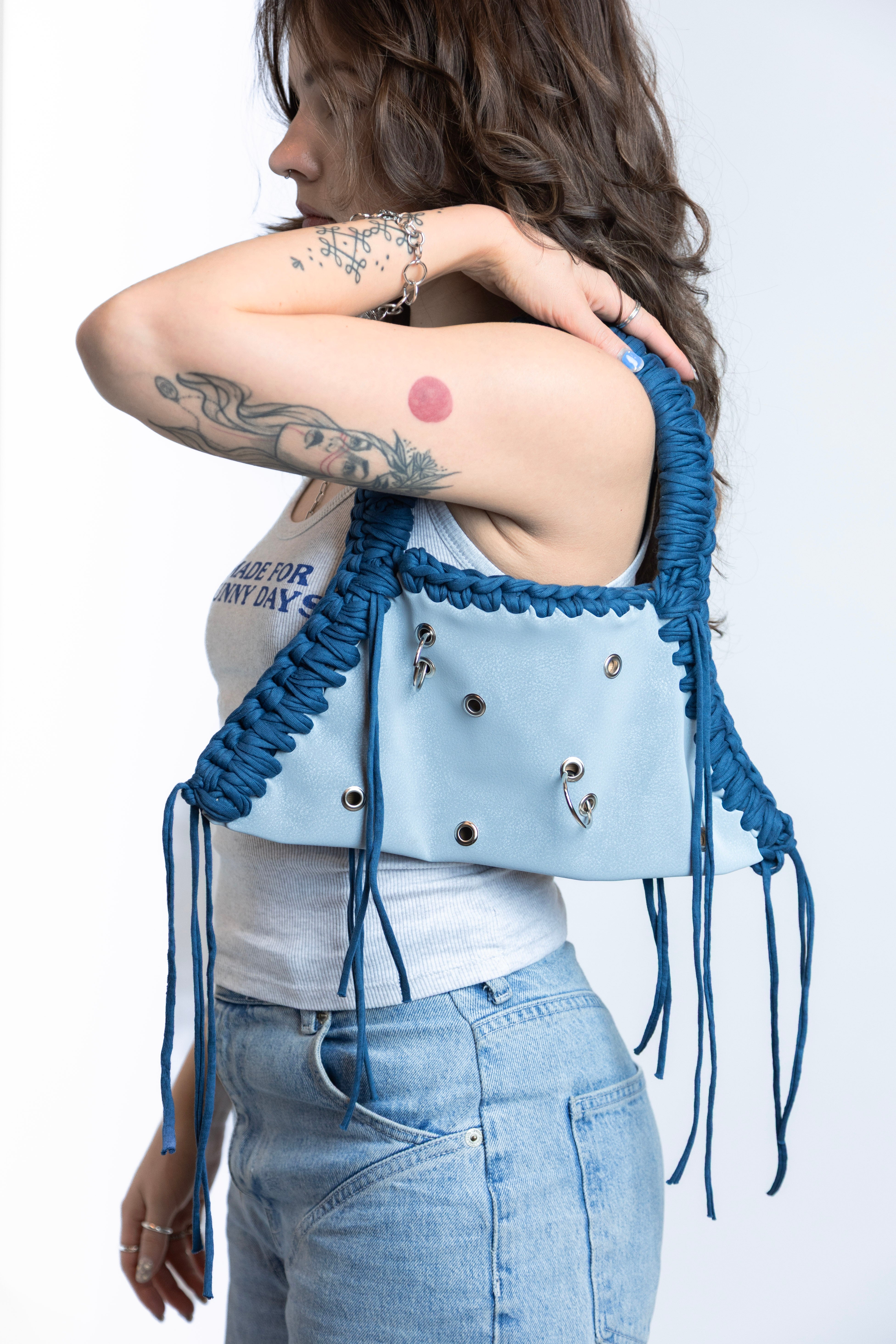 Person wearing a blue fringe vest with a white background