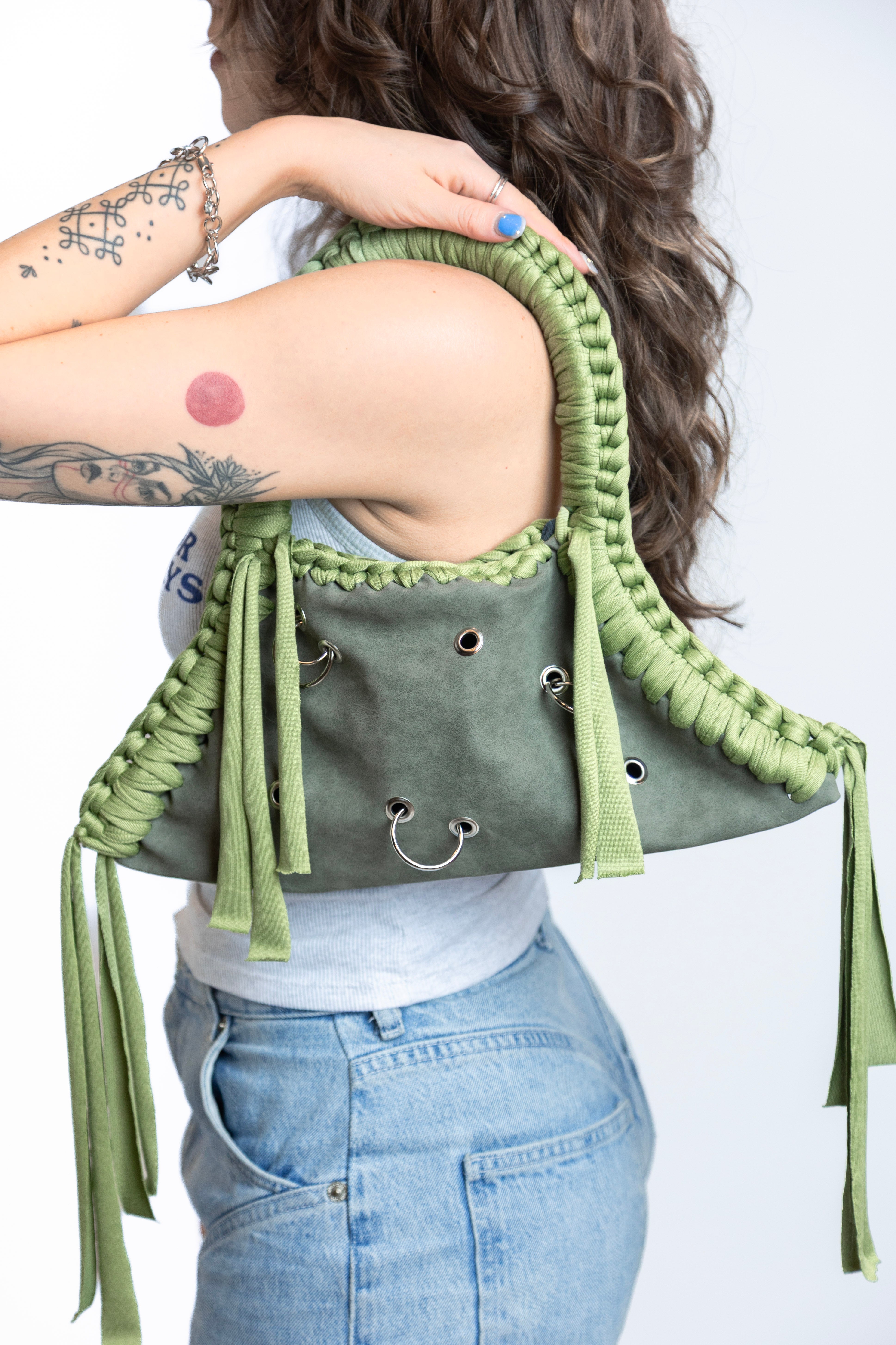 Person wearing a green macramé top with tassels on a white background